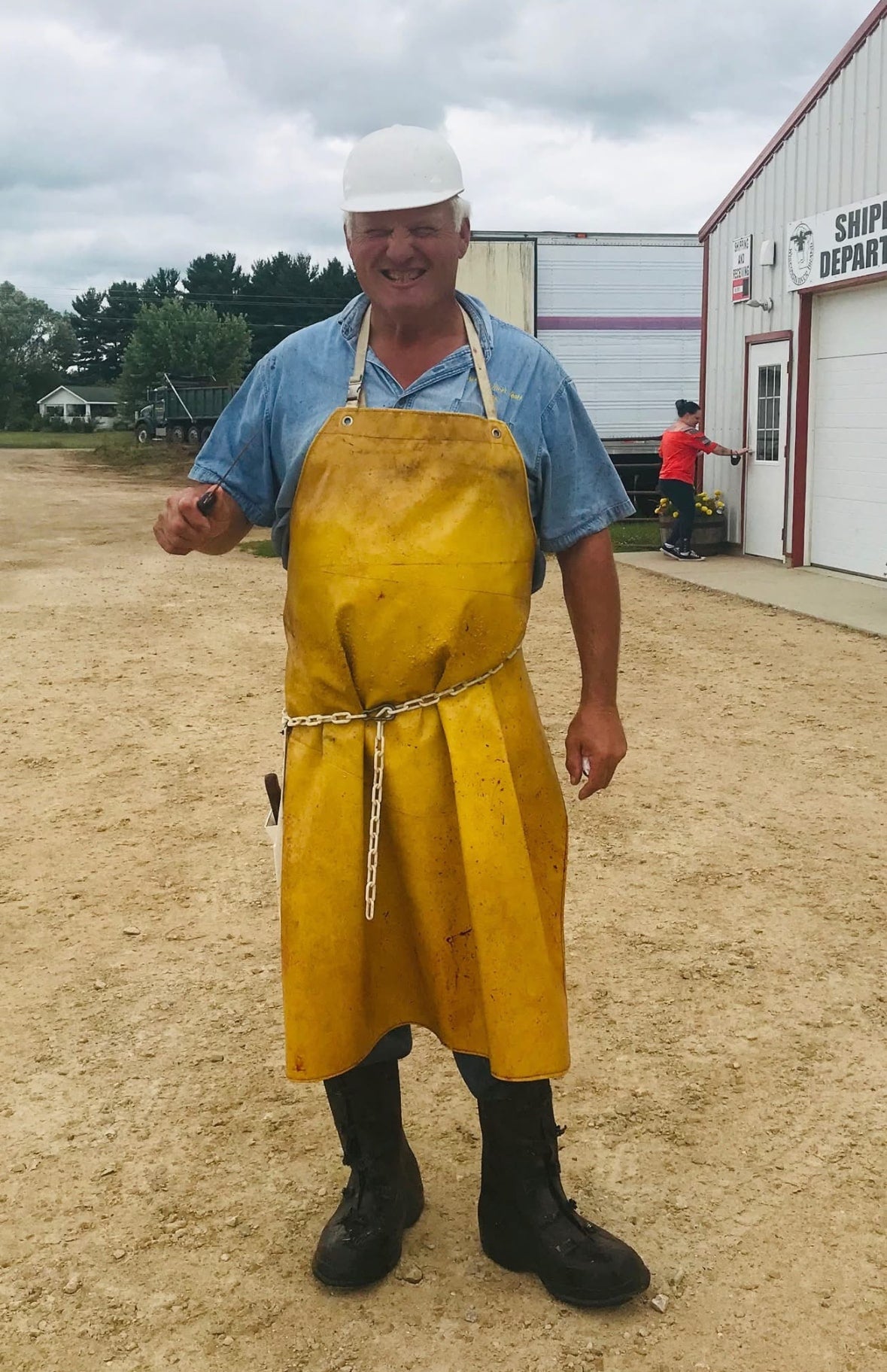 John Hamm, President of Wisconsin River Meats, wearing a hard hat, yellow processing apron, and rubber boots outside the facility.