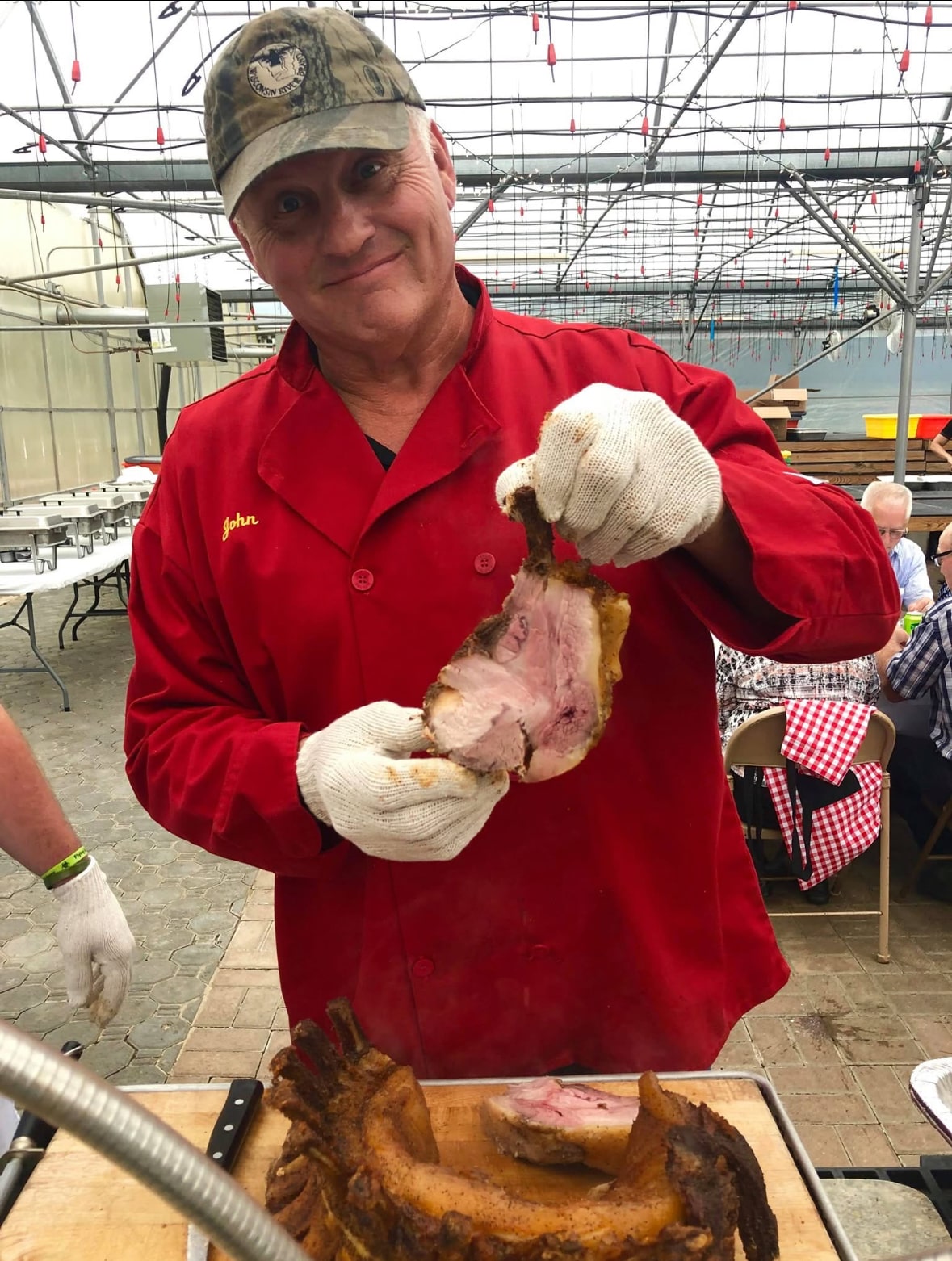 John Hamm, President of Wisconsin River Meats, holding a freshly carved piece of smoked pork at a catered event.