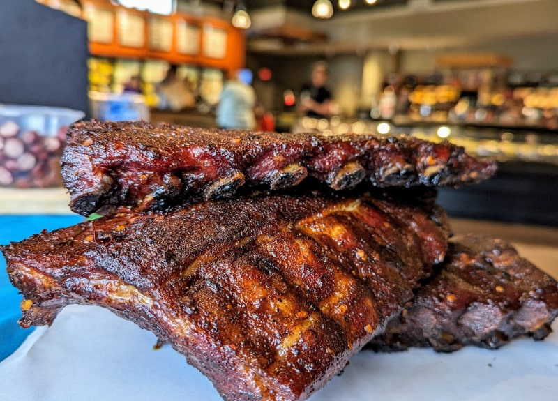 Close-up of seasoned smoked barbecue ribs stacked on butcher paper inside Wisconsin River Meats.
