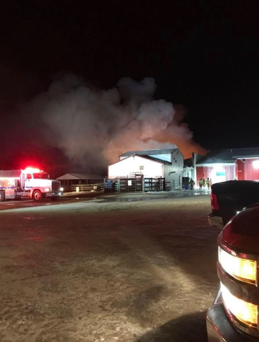 Fire trucks and emergency crews responding as heavy smoke rises from the Wisconsin River Meats facility at night.