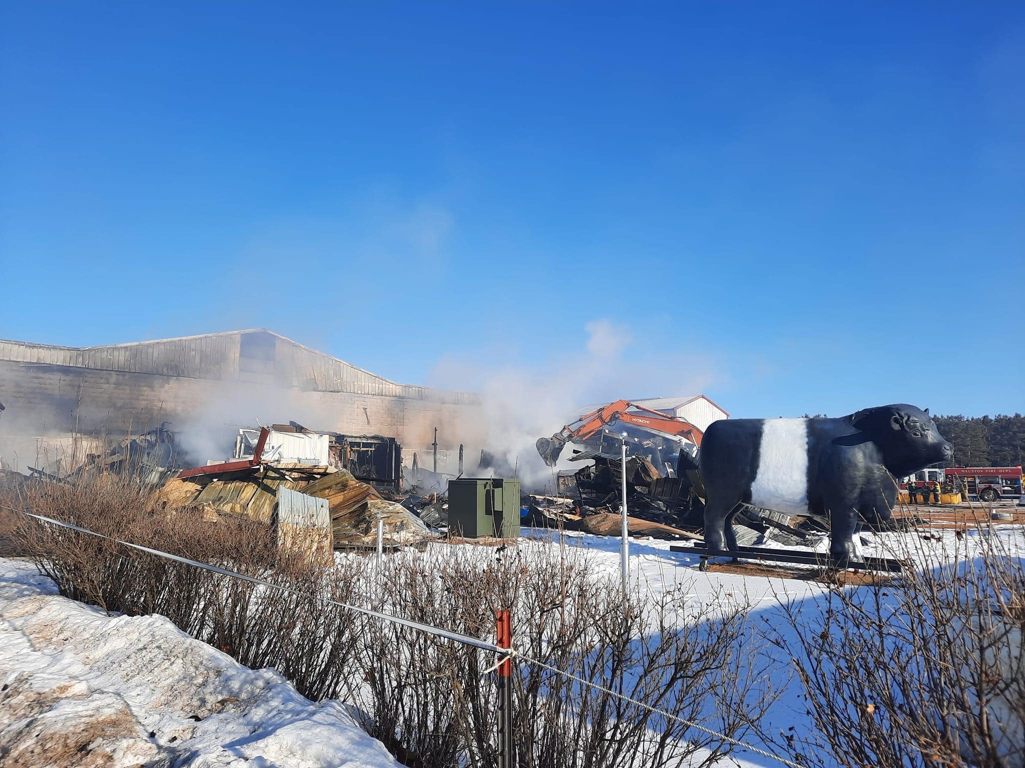 Smoke rising from fire-damaged areas of the Wisconsin River Meats facility as crews begin cleanup and recovery in winter.