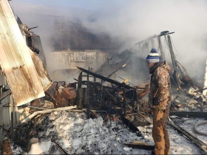 A man surveying the smoking, snow-covered remains of the Wisconsin River Meats facility after the fire.